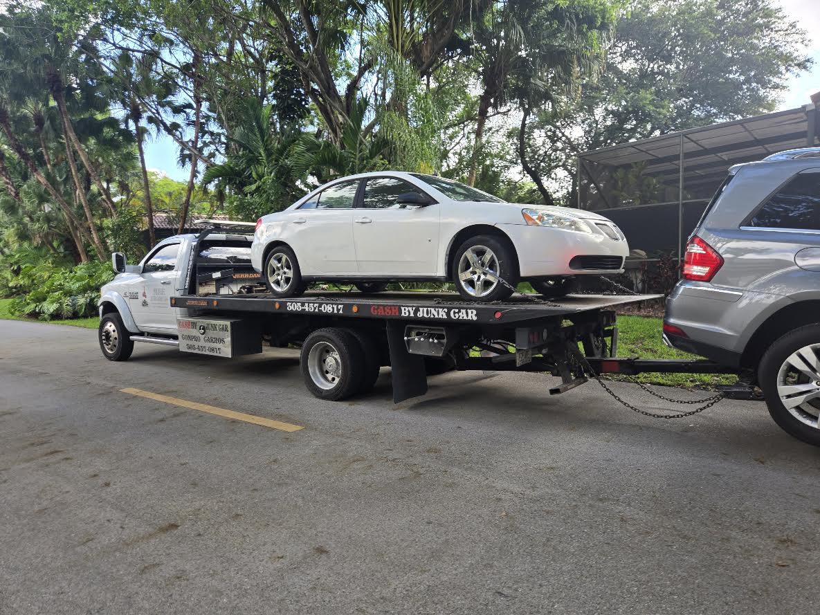 A white sedan on a flatbed truck during a vehicle pickup in Miami